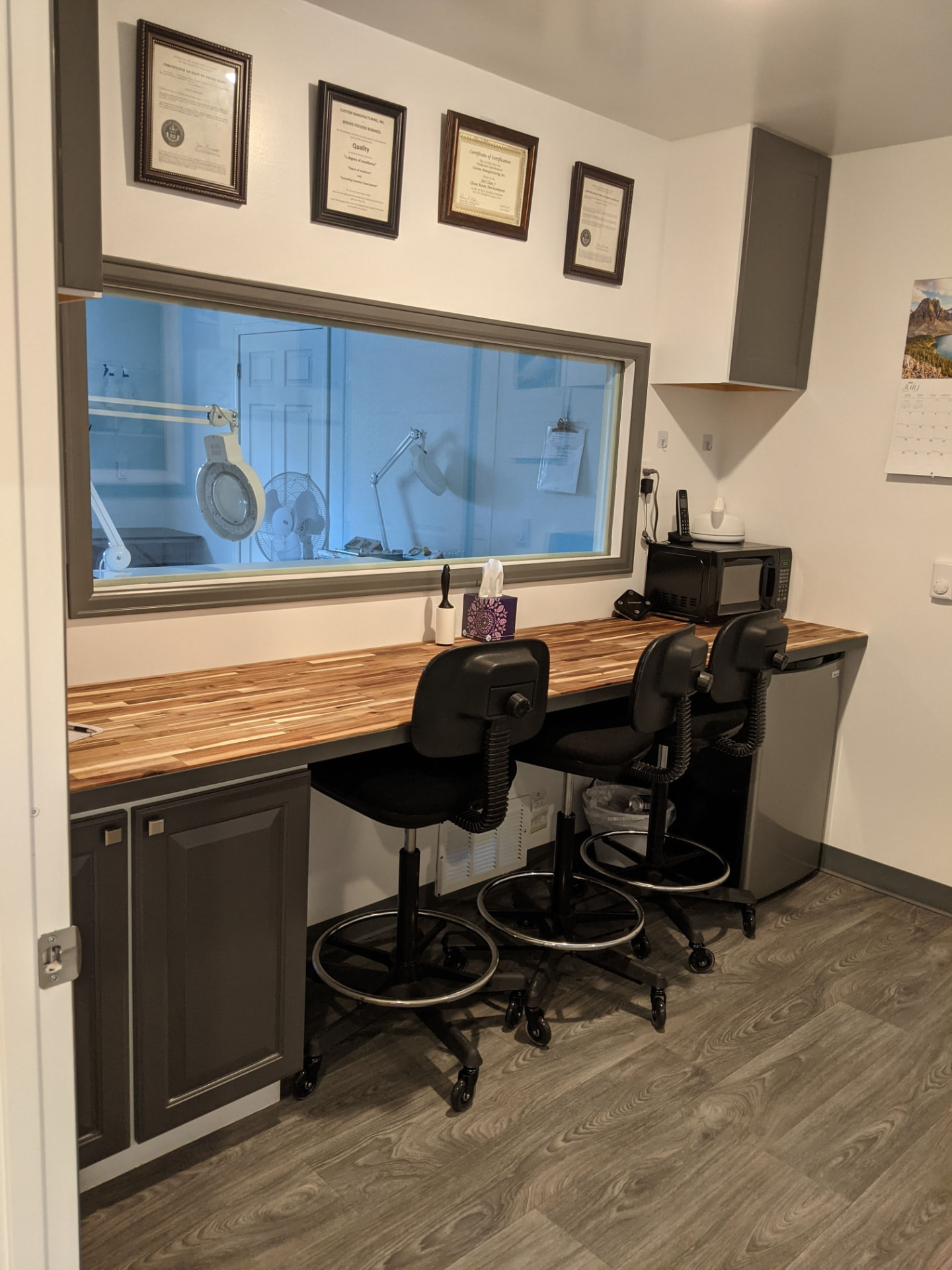 CMI office workstation with framed certifications above the cleanroom observation window